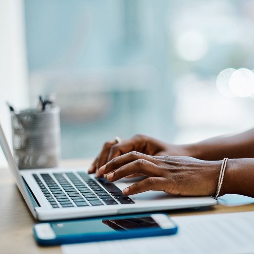 Closeup of a businesswoman typing on a laptop keyboard in an office alone