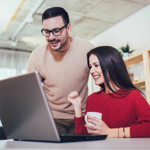 Happy couple doing business together working at small office on the laptop Happy couple doing business together working at small office on the laptop