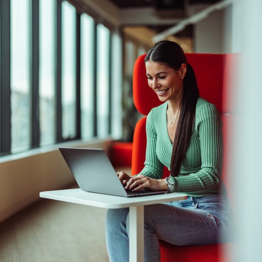 Smiling caucasian woman, writing a report of her job on laptop.