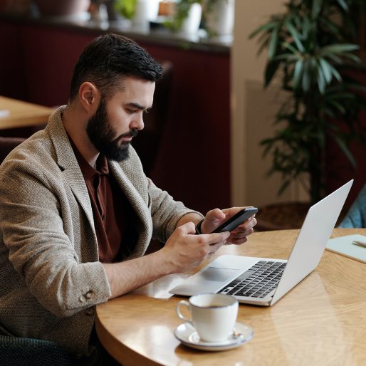 Man in coffee shop looking at mobile_1024x1024